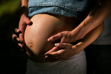 Pai e Mãe segurando o bebê na barriga de gravidez