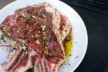 Closeup food photography of raw meat marinading in bowl with fresh herbs