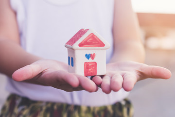 Small kid hands holding house