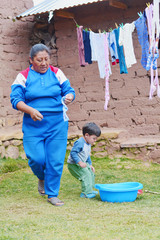 Native american woman with her little son hanging clean clothes outside.