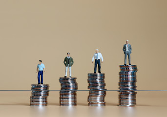 Miniature people standing on piles of coins. Concepts on the difference between promotion and...