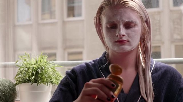 Girl with face mask applying hair oil on her blode hair