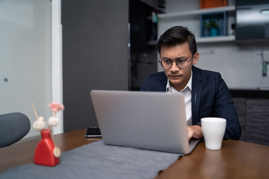 Asian Malay Man Working At Home With Laptop And Calculator