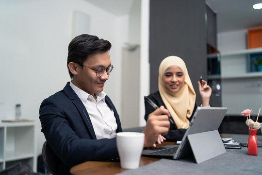 Asian Malay Couple Working Together At Home With Laptop And Calculator