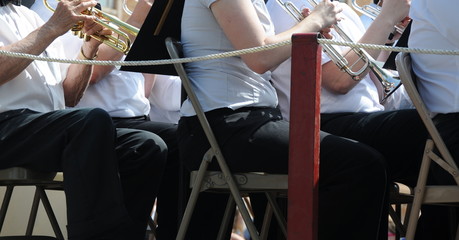 Community band musicians performing on a flat bed truck outdoors.