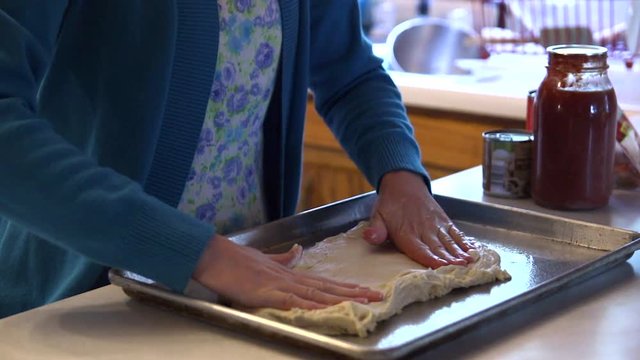 A Mennonite woman kneads dough in her kitchen.