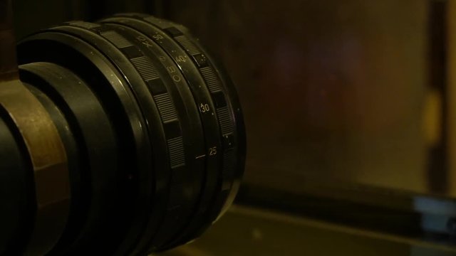 The lens of an old projector that projects a movie