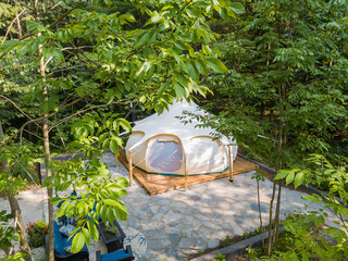 Aerial drone shot of a glamping tent in a forest