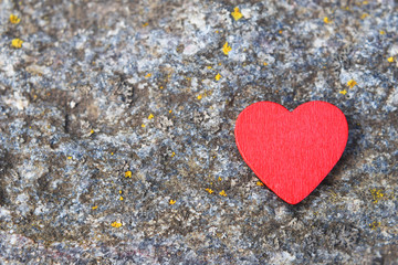 Obraz premium Red wooden heart on grey grunge stone background with copy space for text. Love and valentines day card and healthcare concept.