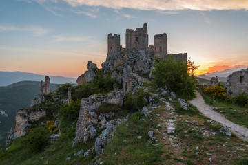 Obraz premium Rocca Calascio (Italy) - The ruins of an old medieval village with castle and church, over 1400 meters above sea level on the Apennine mountains in the heart of Abruzzo, at sunset.