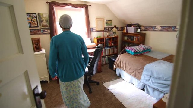 A young Mennonite woman walks into her room and sits down at a computer.