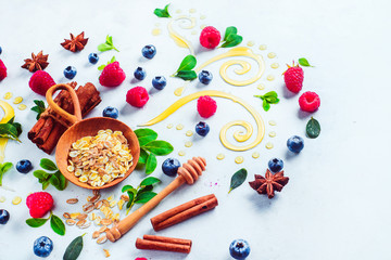 Fototapeta na wymiar Healthy breakfast concept with oatmeal, honey, cinnamon, and berries on a white wooden background. Cooking porridge flat lay with copy space