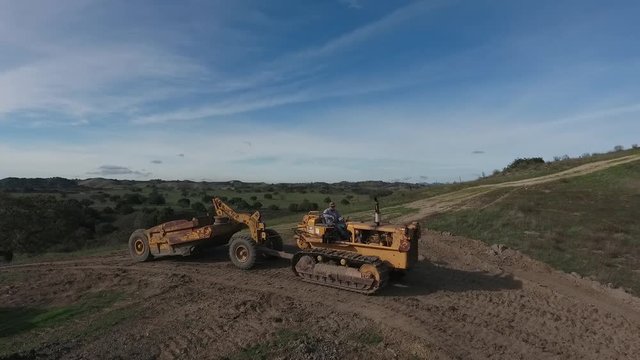 towed scraper hauling mud behind a D5 bulldozer in the green hills
