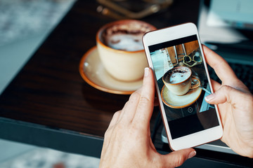Female blogger taking photo of her coffee to make a post