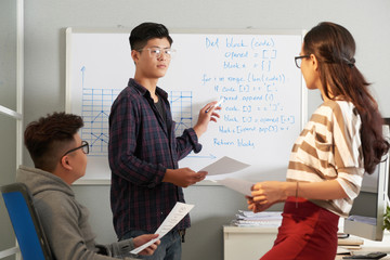 Young programmer discussing block of code with fellow students or coworkers