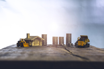 Financial And Macro Economic Concept, pile of coins money stacked on wooden table, with construction vehicle and equipment. Vintage tone.