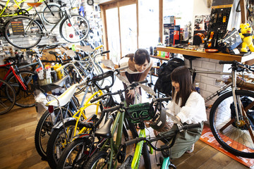ショップ店員と話しながら自転車を選んでいる女性 - obrazy, fototapety, plakaty
