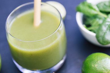 Green smoothie drink with straw dark background closeup