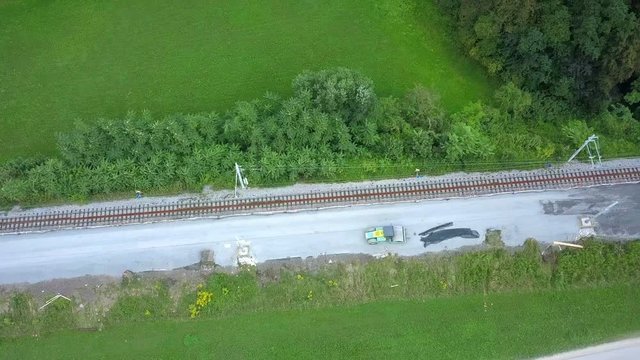 Aerial: Drone flying over railway reconstruction site from birds prespective. Filming rails renovation at railway beside beautiful river on sunny day.