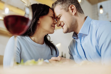 Stay with me. Pleasant smiling man and woman having great time while drinking red wine