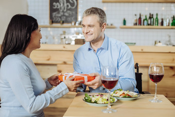 Great surprise. Handsome attractive man giving a gift to a lady while drinking wine