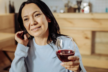 Calm evening. Thoughtful lovely lady raising a glass while thinking about future meeting