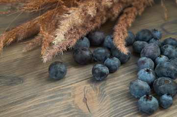 Blueberries and dry flower bouquet on wooden board