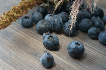 Blueberries and dry flower bouquet on wooden board