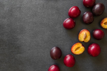 Beautiful, fresh whole and half of plums on the dark background. Healthy sweet food concept. Mock up for fruits offers as advertising or web background, or other ideas. Empty place for text or logo.