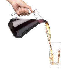 Hand pouring cola from glass jug to glass isolated on a white background