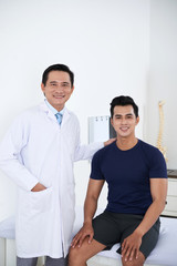 Obraz premium Happy Vietnamese chiropractor and his smiling young patient
