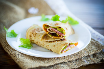 thin pancakes with salad leaves and bacon in a plate