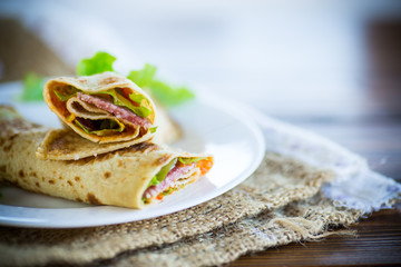 thin pancakes with salad leaves and bacon in a plate