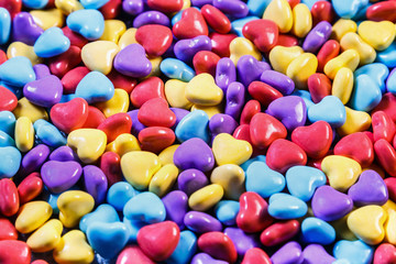 different colors of chewing gum and candy in the shape of a heart. background of sweets