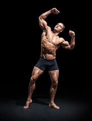 Fototapeta premium Athletic man posing. Photo of man with perfect physique on black background. Strength and motivation