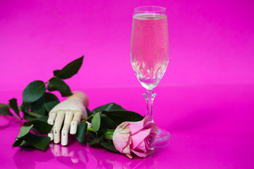 Glass of champagne on pink background with roses