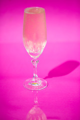 Glass of champagne on pink background