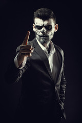 Portrait of man with Halloween skull makeup on the black background.