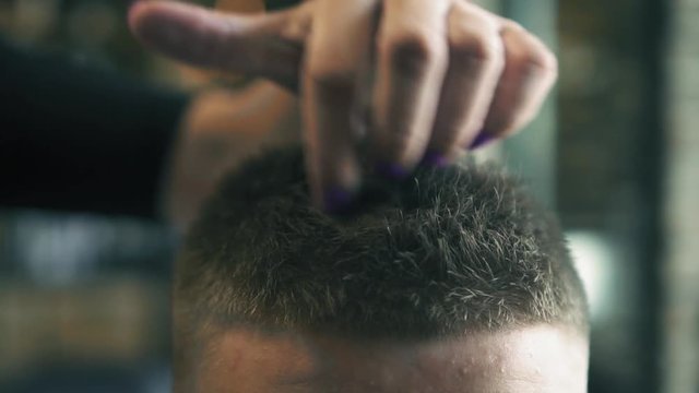 Woman barber is doing man's hair styling in barbershop with hands and hair gel. Slow motion. Close up.