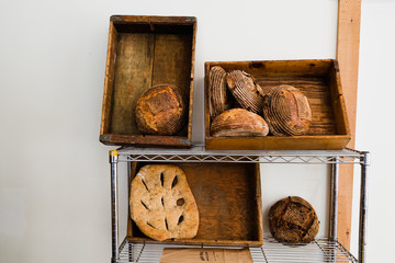 Artisan bread on a shelf against a white wall.