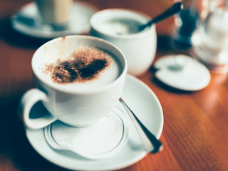 Coffee table with a cup of coffee with milk foam and cocoa powder, cappuccino.