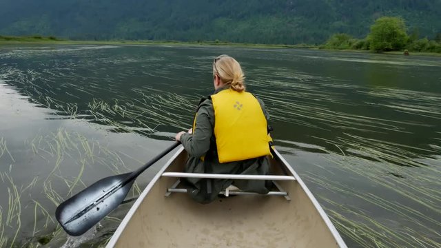 Woman paddling canoe on mountain lake