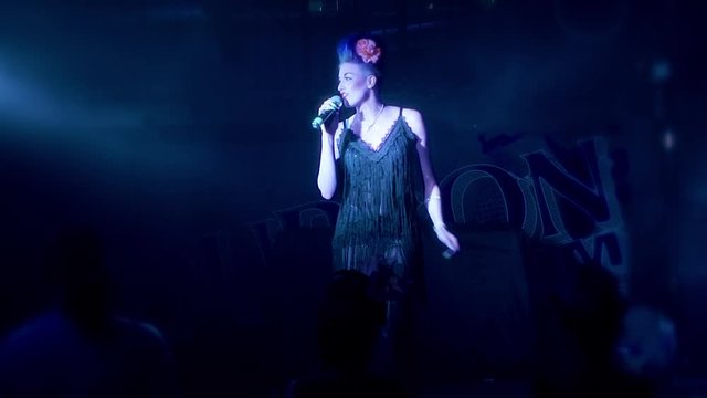 Beautiful retro female singer on stage in a smokey bar wearing a flapper dress