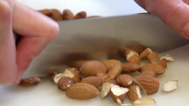 Chef cutting almonds with a knife.