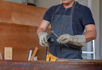 Worker in workwear welding the steel part by manual with safety equipment