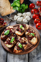 Appetizer bruschetta with sun-dried tomatoes, olives and mozarel