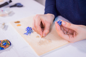 Professional jewelry designer making handmade eardrop with beads in studio, workshop. Fashion,...