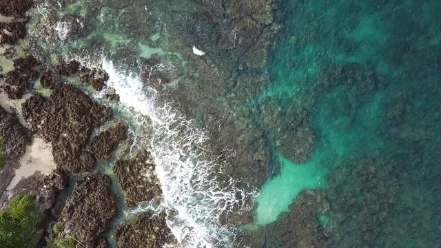 Aerial shot flying above lush green coastline and teal blue ocean waves in Kenting, Taiwan