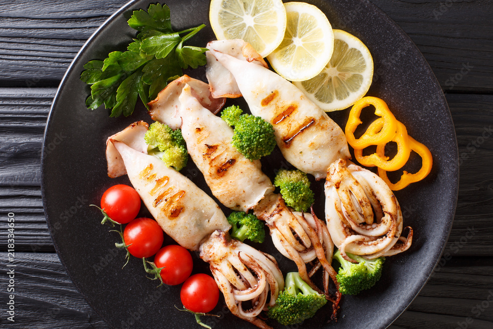 Wall mural healthy food seafood: grilled squid with fresh vegetables close-up on a plate on a wooden. horizonta