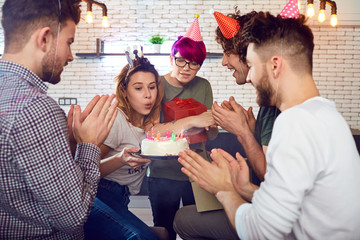 A group of young people students with birthday cake celebrate indoors.